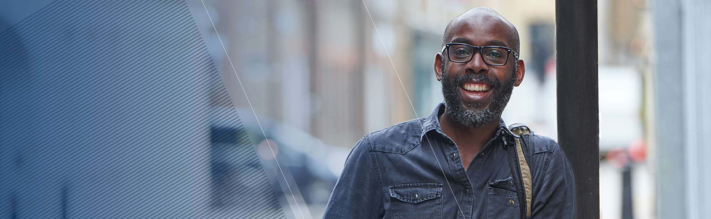 Man with beard and glasses smiling while standing outside